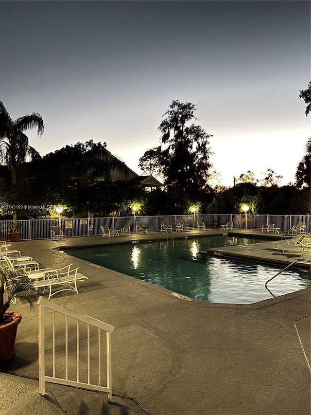 pool at dusk featuring a patio