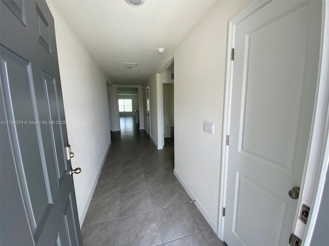 hallway featuring a textured ceiling and light tile patterned flooring