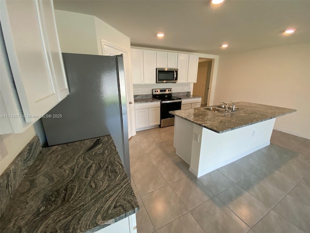 kitchen featuring sink, dark stone countertops, appliances with stainless steel finishes, a kitchen island with sink, and white cabinets