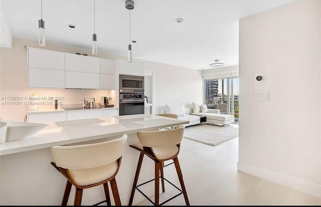 kitchen with pendant lighting, a kitchen bar, white cabinetry, and appliances with stainless steel finishes