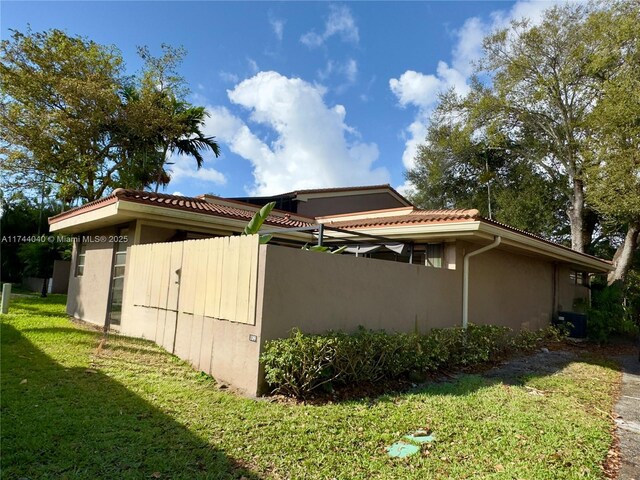109 Heatherbrook Way Unit 146, Hollywood, FL 33021 - view of property exterior with a tiled roof, stucco siding, a yard, and fence