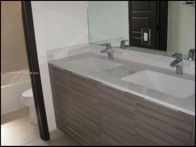 bathroom with double vanity, tile patterned flooring, a sink, and toilet