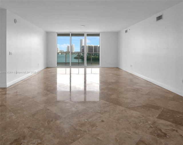 spare room featuring floor to ceiling windows and a water view