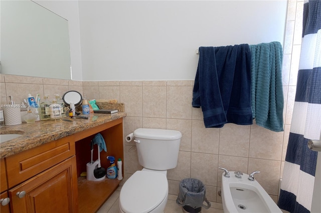 bathroom featuring vanity, toilet, tile walls, and a bidet