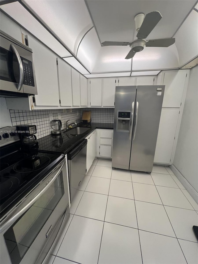 kitchen with sink, light tile patterned floors, appliances with stainless steel finishes, decorative backsplash, and white cabinets