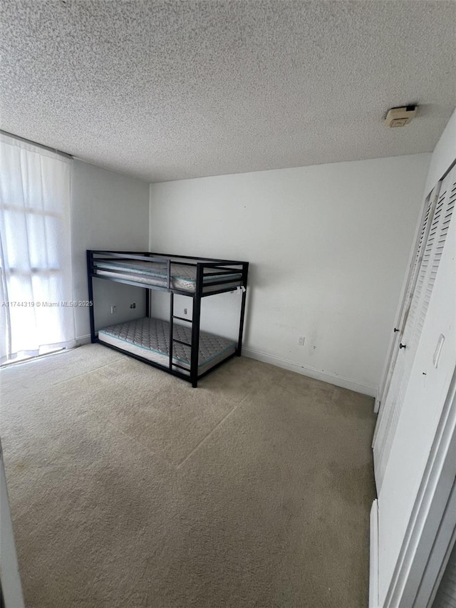 bedroom with light colored carpet and a textured ceiling