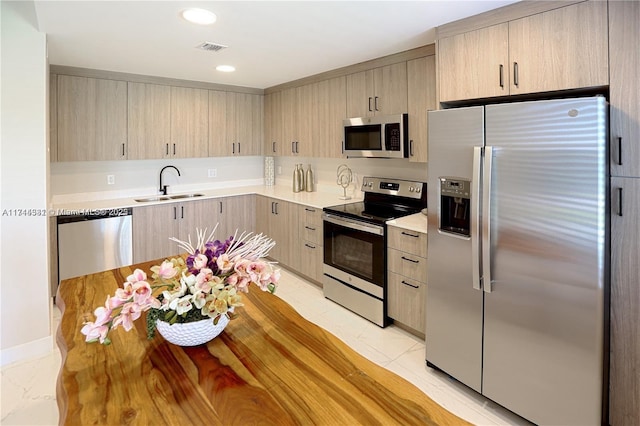 kitchen featuring appliances with stainless steel finishes, sink, and light brown cabinets