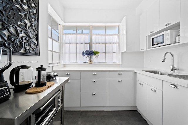 kitchen with white cabinetry, sink, and dark tile patterned flooring