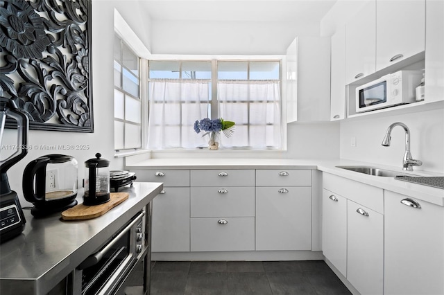 1005 Meridian Ave Unit 7, Miami Beach, FL 33139 - kitchen with white microwave, light countertops, dark tile patterned floors, and white cabinets