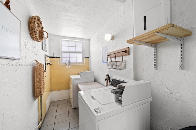 1005 Meridian Ave Unit 7, Miami Beach, FL 33139 - laundry room with washer and clothes dryer, light tile patterned flooring, a textured ceiling, tile walls, and a textured wall