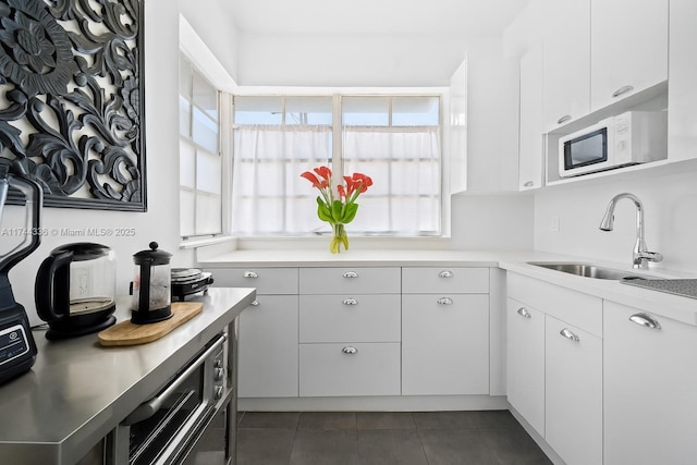 1005 Meridian Ave Unit 7, Miami Beach, FL 33139 - kitchen with white microwave, light countertops, white cabinetry, and dark tile patterned flooring