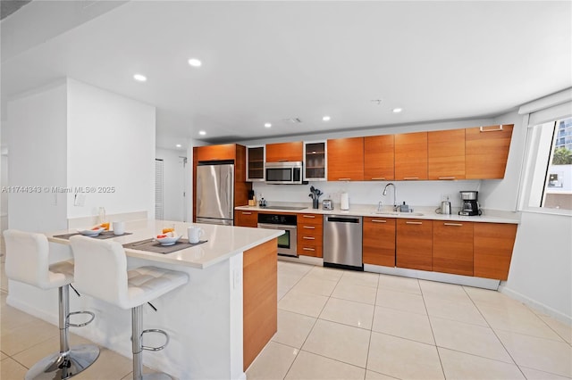 kitchen with stainless steel appliances, sink, a breakfast bar area, and light tile patterned floors
