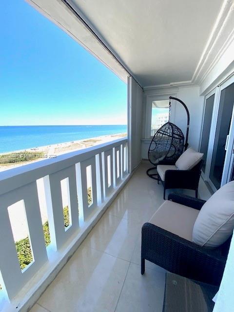 balcony featuring a water view and a beach view