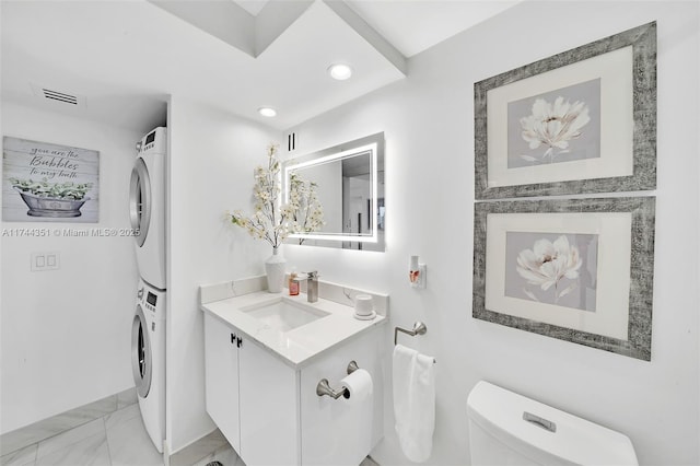1012 N Ocean Blvd Unit 701, Pompano Beach, FL 33062 - half bath featuring stacked washing machine and dryer, vanity, toilet, marble finish flooring, and recessed lighting
