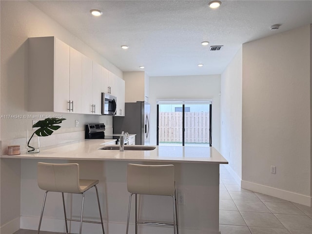 kitchen with white cabinetry, appliances with stainless steel finishes, a breakfast bar, and kitchen peninsula