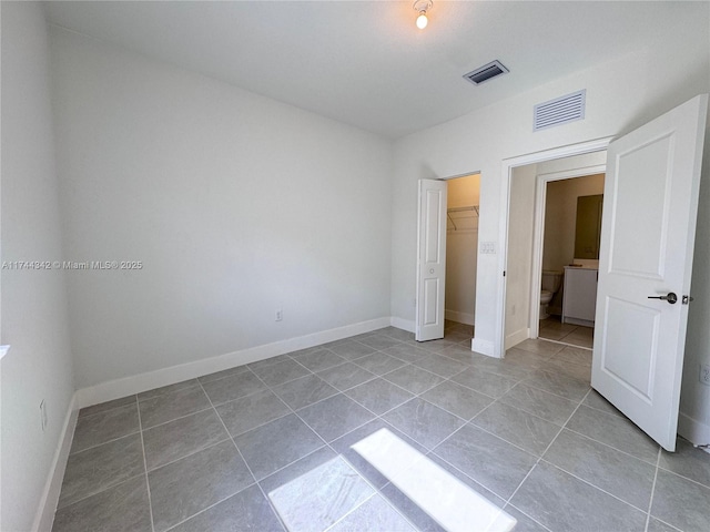 unfurnished bedroom with a walk in closet, a closet, and light tile patterned floors