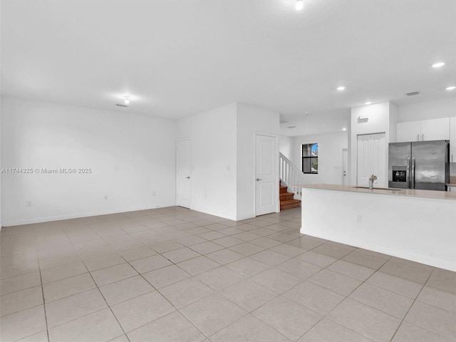 unfurnished living room featuring sink and light tile patterned floors