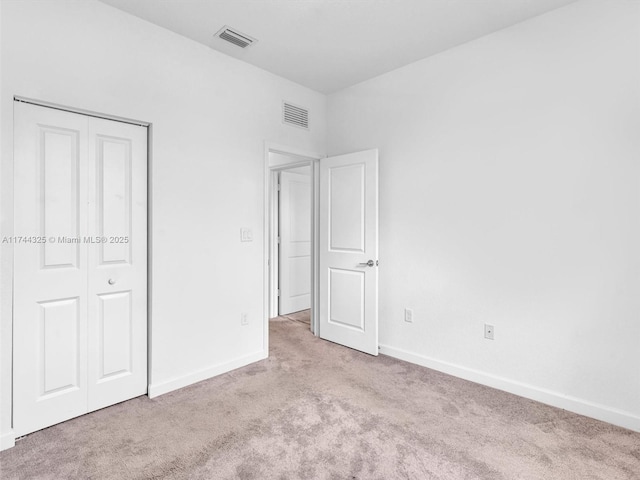 unfurnished bedroom featuring light colored carpet and a closet