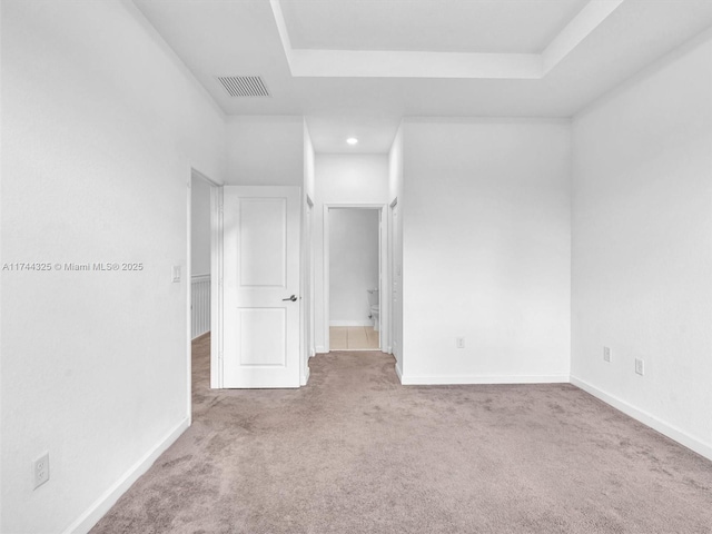 empty room with carpet floors and a tray ceiling