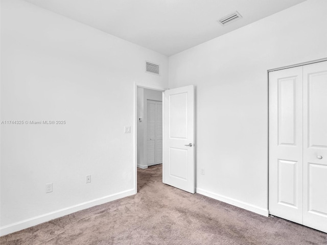 unfurnished bedroom featuring light colored carpet and a closet