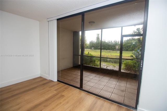 interior space featuring a healthy amount of sunlight, baseboards, wood finished floors, and a wall of windows