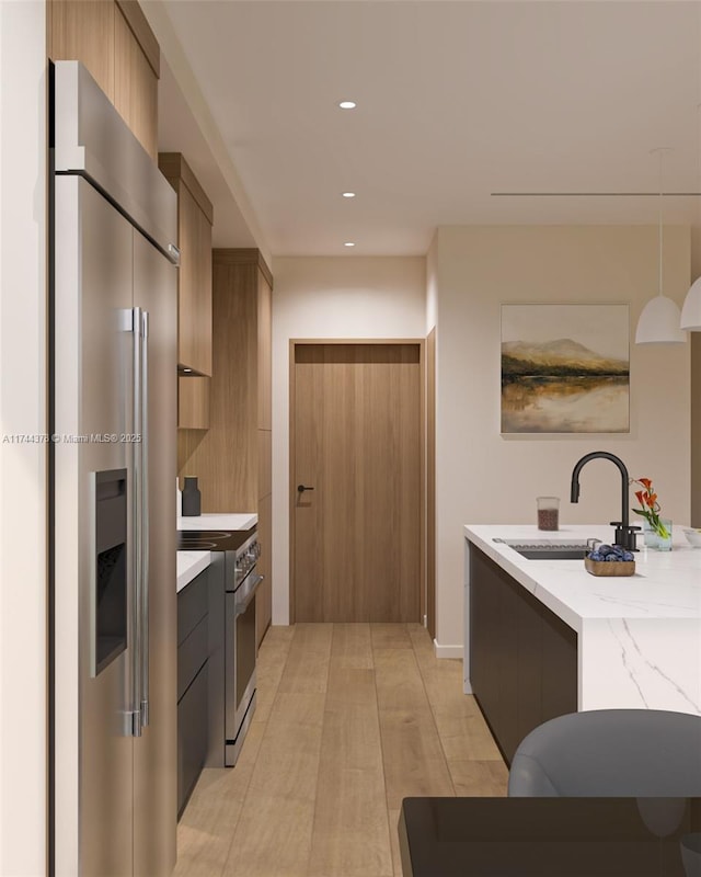 kitchen with a sink, recessed lighting, modern cabinets, light stone countertops, and appliances with stainless steel finishes