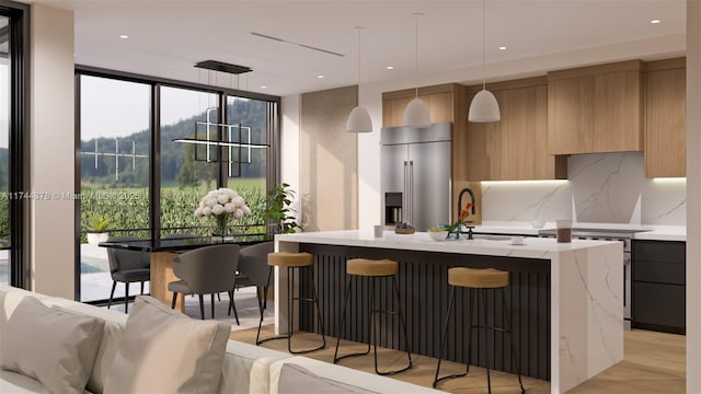 kitchen with tasteful backsplash, a kitchen island with sink, modern cabinets, high quality fridge, and a wall of windows