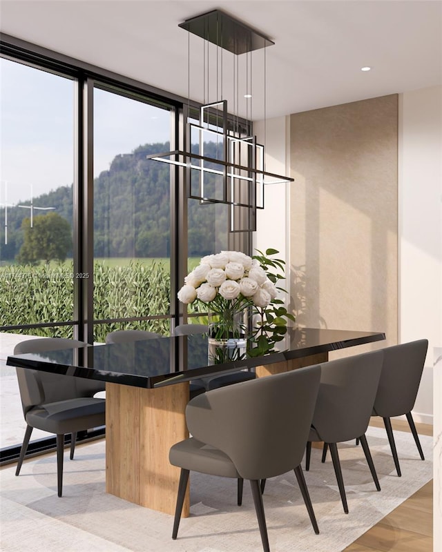 dining area featuring expansive windows, light wood-style flooring, and an inviting chandelier