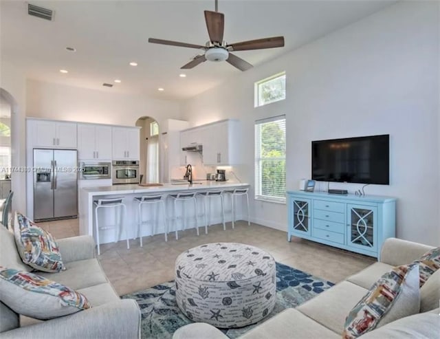 living room featuring ceiling fan, sink, and light tile patterned floors