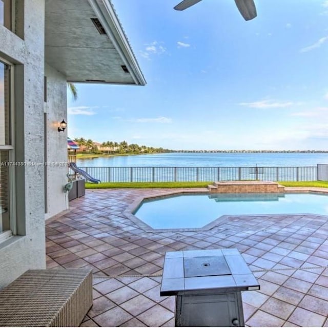 view of swimming pool with a patio, ceiling fan, and a water view