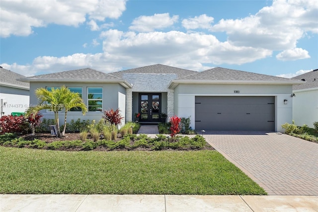 view of front of property with decorative driveway, french doors, a garage, and stucco siding