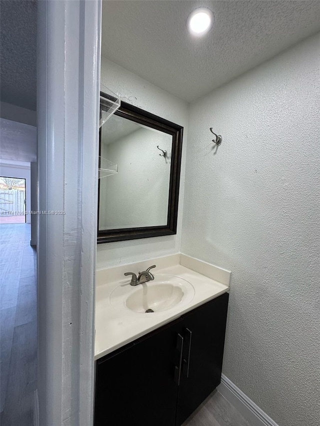10800 NW 7th St Unit 3B, Miami, FL 33172 - bathroom featuring a textured wall, baseboards, vanity, and a textured ceiling