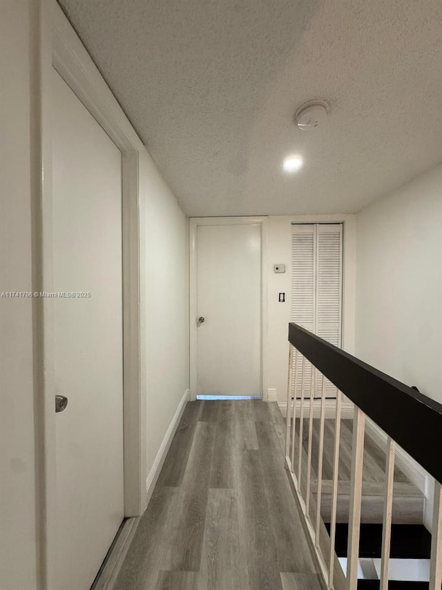 10800 NW 7th St Unit 3B, Miami, FL 33172 - hallway featuring wood finished floors, a textured ceiling, baseboards, and an upstairs landing