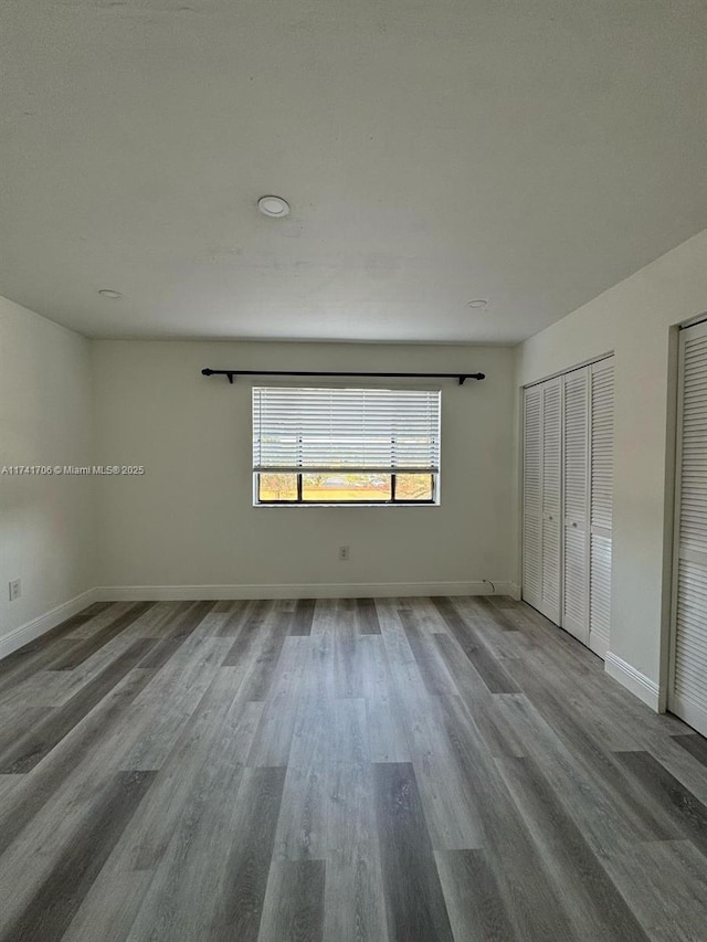 10800 NW 7th St Unit 3B, Miami, FL 33172 - unfurnished bedroom with wood finished floors, baseboards, and two closets