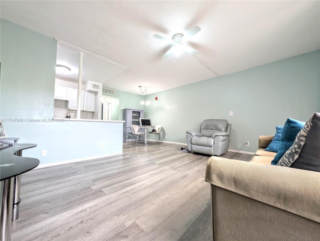 living room featuring ceiling fan, light hardwood / wood-style floors, and a textured ceiling