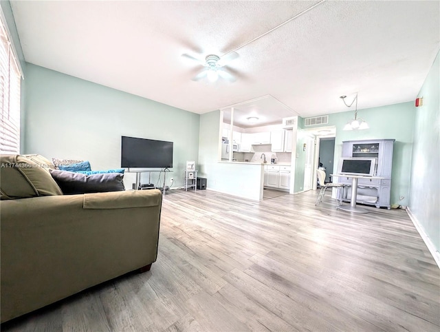 living room with a textured ceiling, light hardwood / wood-style flooring, and ceiling fan