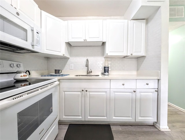 kitchen with tasteful backsplash, white cabinetry, sink, light hardwood / wood-style floors, and white appliances