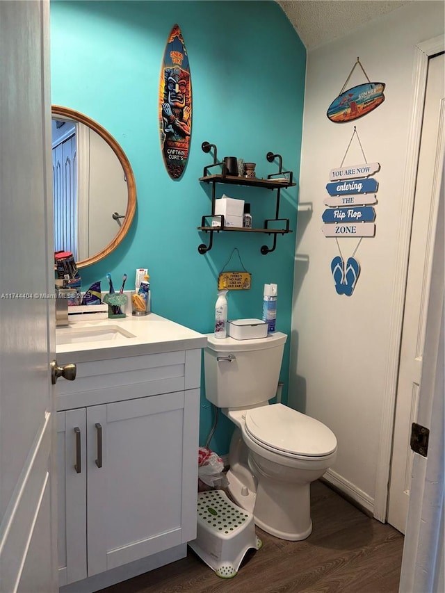 bathroom featuring hardwood / wood-style flooring, vanity, toilet, and a textured ceiling