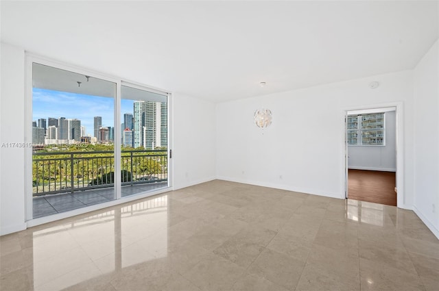 unfurnished room featuring a view of city, floor to ceiling windows, and baseboards