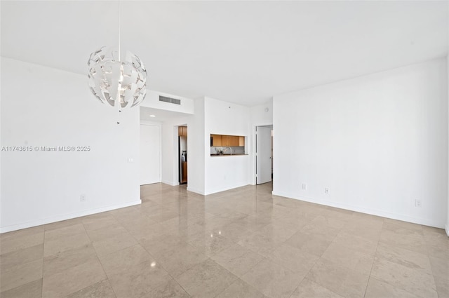 unfurnished room with visible vents, baseboards, and an inviting chandelier