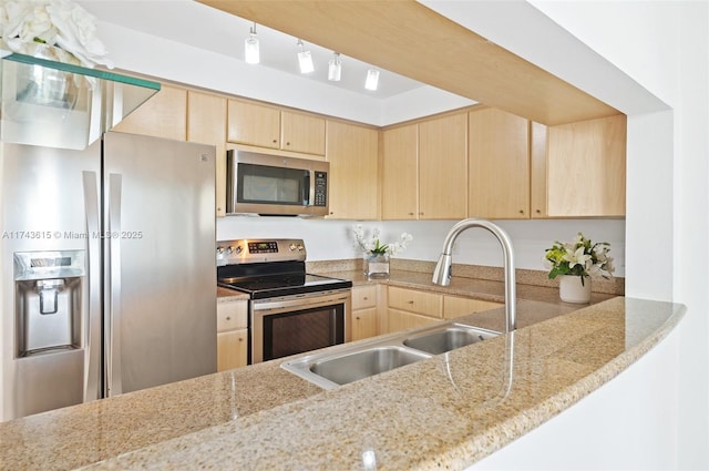 kitchen with stainless steel appliances, light brown cabinetry, a peninsula, and a sink