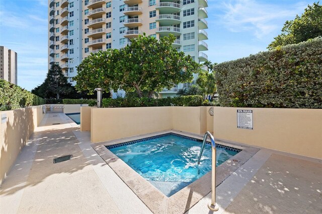 view of pool featuring a community hot tub and fence