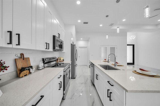 kitchen featuring decorative light fixtures, light stone countertops, white cabinets, and appliances with stainless steel finishes