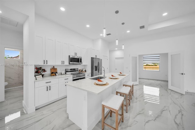 kitchen with pendant lighting, sink, a kitchen island with sink, stainless steel appliances, and a kitchen breakfast bar