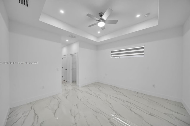 empty room featuring ceiling fan and a tray ceiling