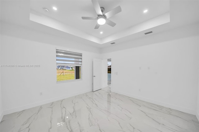 empty room featuring a raised ceiling and ceiling fan