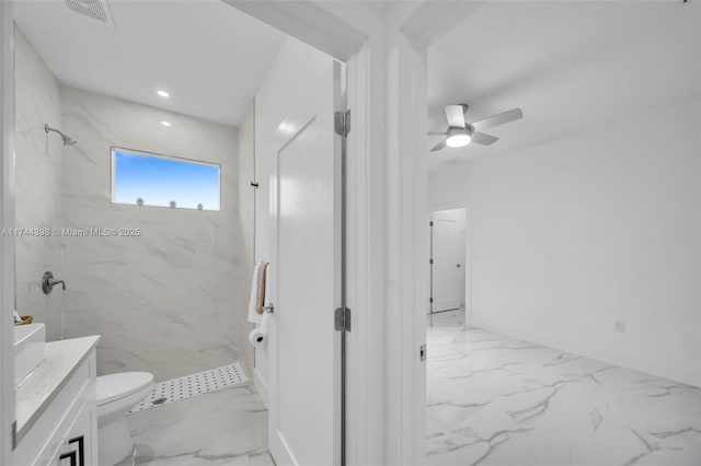 bathroom with ceiling fan, tiled shower, vanity, and toilet