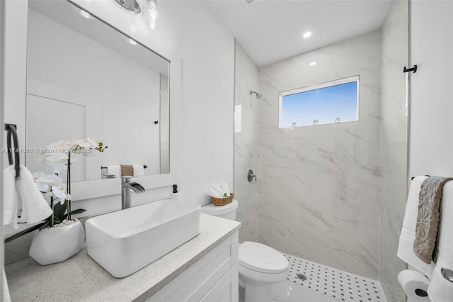 bathroom with vanity, toilet, and a tile shower