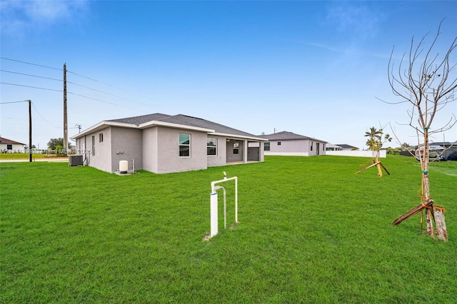 rear view of property with central AC and a lawn