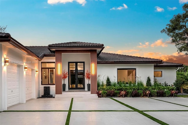 back house at dusk featuring a garage